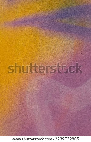 Fragment of old plaster wall with graffiti painting. Part of colorful street art graffiti on wall background. Youth, urban culture. Yellow, green, purple, light blue colors.