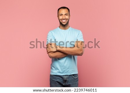 Confident man. Portrait of happy african american guy standing with folded arms and smiling, posing isolated over pink studio background. Happy casual male model looking at camera