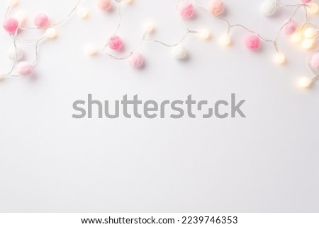 Saint Valentine's Day concept. Top view photo of light bulb garland and soft pompons on isolated white background with empty space