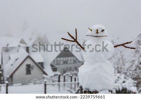 Photo of Happy small snowman against the background of a snowy city