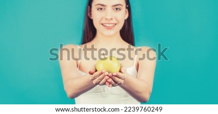 Healthy diet food. Woman with perfect smile holding apple, blue background.