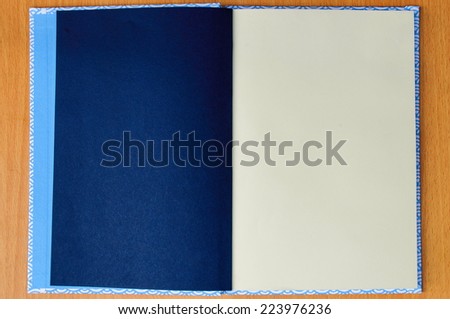 a blue notebook is open white page on the brown wood background