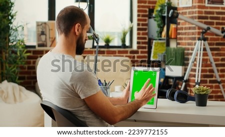 Office worker working with isolated greenscreen display on wireless device, using chroma key template and mock up blank background. Looking at copy space screen on digital tablet.