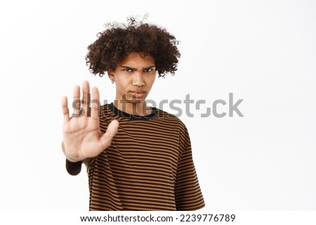 Enough, stop it. Serious hispanic guy extends one hand, rejects, disapprove smth, prohibit action, stands over white background