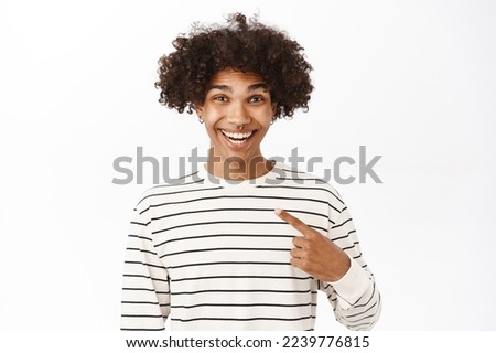 Close up portrait of smiling handsome man pointing finger at himself, self-promoting, talking about him, standing over white background