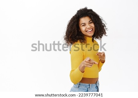 Congrats its you. Smiling african american girl pointing fingers at camera and congratulating, inviting people, praising or complimenting, standing over white background