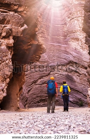 Two young backpackers watching sunbeams in the hollow of the Quebrada das Conchas amphitheater in Cafayate, Argentina Royalty-Free Stock Photo #2239811325
