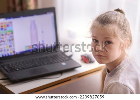little blonde girl plays on a laptop in her room