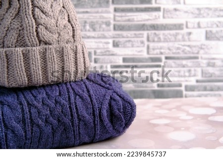 a knitted hat made of grey wool lies on a dark purple wool sweater