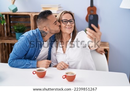 Man and woman mother and son drinking coffee make selfie by smartphone at home