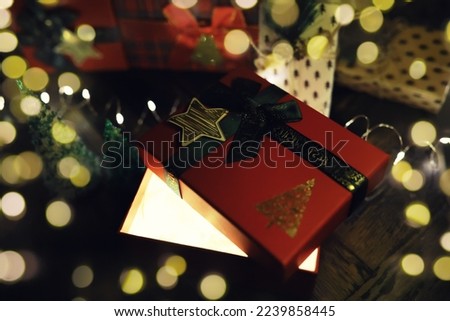 Gift boxes with a large red bow  against a background bokeh of twinkling party lights. Luxury New Year gift. Christmas gift. Christmas background with gift box. Christmastime celebration