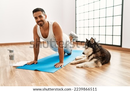 Young hispanic man smiling confident training with dog at sport center