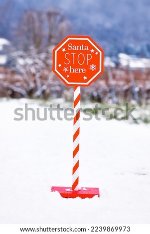 Christmas sign with text 'Santa Stop here' in snowy landscape