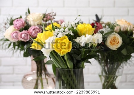 Beautiful bouquets with fresh flowers against white brick wall, closeup