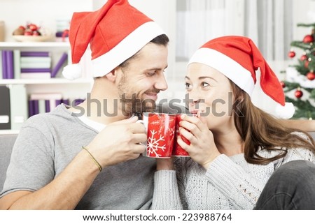 young christmas couple relaxing and enjoying hot tee on sofa and love each other