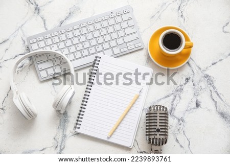 Notebook with headphones, microphone, coffee cup and computer keyboard on grunge background. Podcast concept