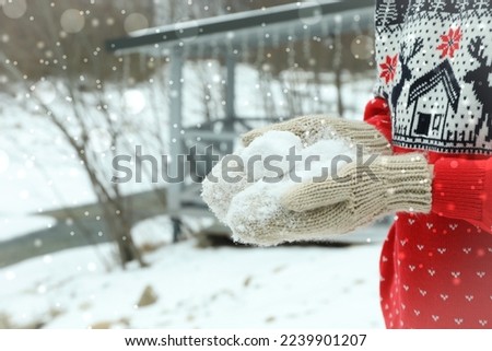 Woman in mittens holds snow outdoor, space for text