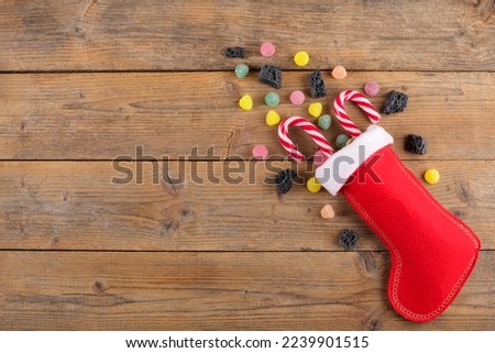 Red Epiphany Befana's stocking with sweet coal and candy on rustic wooden background, Italian Epiphany day tradition for children to give a stocking full of sweets. Top view, flat lay, close up