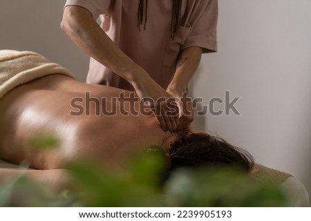 Close-up of the masseur's hands doing a back massage to a woman in the salon in a cozy atmosphere. Concept of a healthy lifestyle and body care.