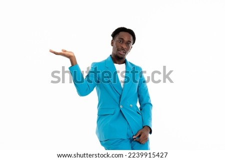 Portrait of african american man model looking at camera wearing casual blue suit and white t-shirt posing for came on white copy space in studio isolated presenting idea with hands. Royalty-Free Stock Photo #2239915427