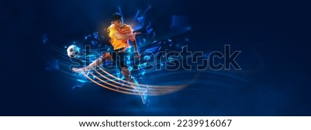 Portrait of young man football athlete kick football ball over dark blue background with polygonal and fluid neon elements. Concept of sport, activity, creativity. Copy space for ad, text