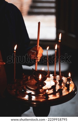 a young girl lighting a candle in a church in the name of the health of loved ones, the front and background are blurred with a bokeh effect