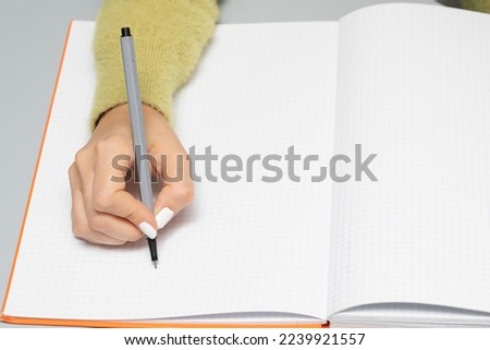Hand of woman who is about to write on an empty page of notebook with a black marker. Large copyspace and space to add advertising text