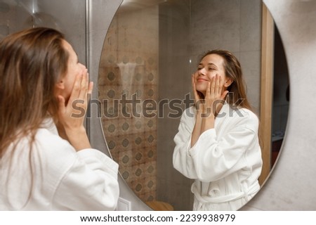 Woman doing morning facial skin massage, moisturizing cream and mask, care daily morning routine Royalty-Free Stock Photo #2239938979
