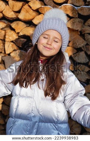 little girl in a gray knitted hat and scarf in winter outdoors, outside, winter season