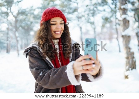 Happy woman taking selfie in winter forest. Young tourist with phone. Selfie time.Travelling, lifestyle, adventure, holidays concept.
