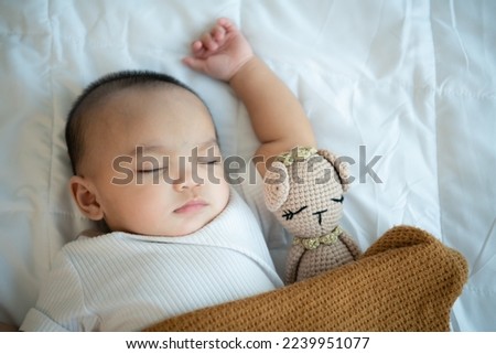 Young mother hugging her newborn child to lull the baby to sleep in the white bedroom, warm sunlight in the evening of the day.
