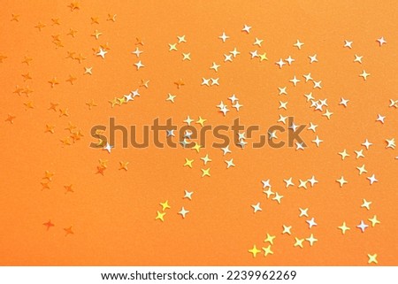 Shiny bright glitter on orange background, top view Royalty-Free Stock Photo #2239962269
