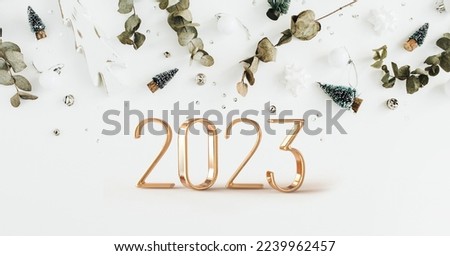 Happy new year 2023. White paper numbers with golden Christmas decoration and confetti on dark blue background. Holiday greeting card design.
