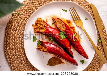 Traditional Serbian festive and lean lunch idea, dried stuffed peppers with walnuts, rice and spices served on a white plate with golden rim with gold cutlery top view Royalty-Free Stock Photo #2239980801