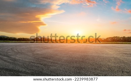 Asphalt race track road and green forest with sky clouds at sunset