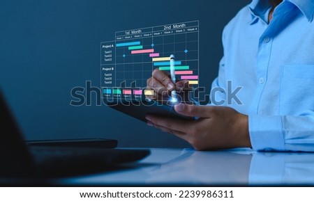 Project manager working on tablet and updating tasks and milestones progress planning with Gantt chart scheduling interface for company on virtual screen. Business Project Management System. Royalty-Free Stock Photo #2239986311