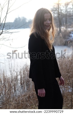 Young girl in black elegance wear walk in the winter forest. Sunset and snow
