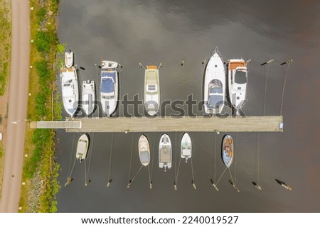 An aerial shot of boats parked at the wooden dock on the river in the daylight