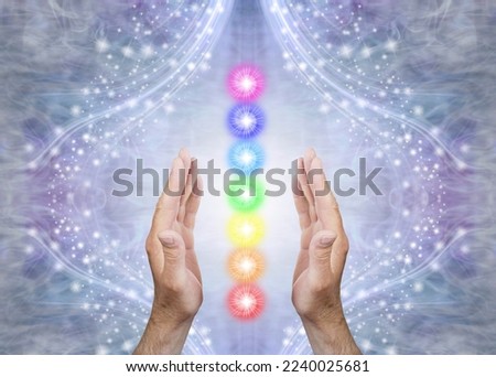 Sensing Seven Chakras and Sending Healing - Male parallel hands with 7 rainbow coloured energy centres between against a blue flowing sparkling background and copy space 
 Royalty-Free Stock Photo #2240025681