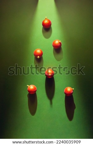 Creative holiday card with Christmas tree shape shadow and red ornaments on deep green background. Minimal xmas concept.