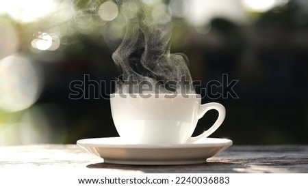 Close-up white coffee cup, mug with steaming smoke of coffee on old wooden table in morning nature outdoor, garden background, 4K. Hot Coffee Drink, Beverage Concept. Royalty-Free Stock Photo #2240036883