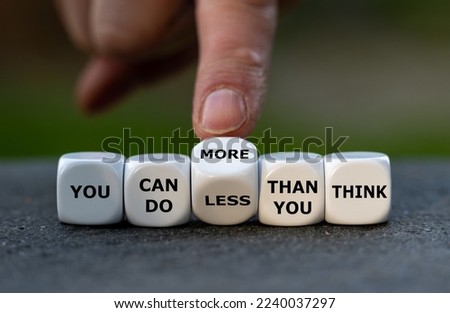 Hand turns dice and changes the expression 'you can do less than you think' to 'you can do more than you think'. Royalty-Free Stock Photo #2240037297
