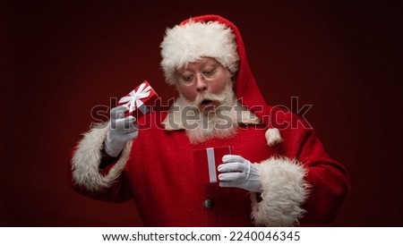 Santa Claus open one gift box with suprised funny facial expression