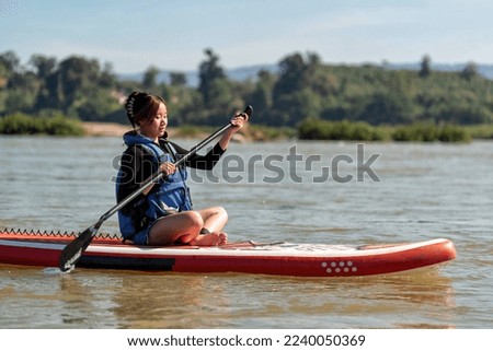 Beautiful girl on holiday activity paddling on a sup boards on a large river on summer day