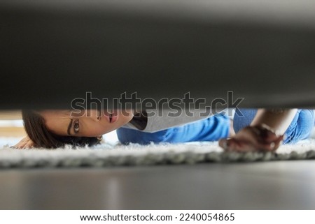 Woman, confused and couch looking for lost product in her home living room with doubt. Female, floor and checking under sofa for a missing item and searching her apartment or house in the carpet Royalty-Free Stock Photo #2240054865