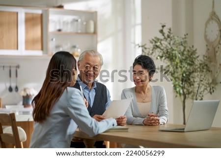 young asian door to door saleswoman selling product or service to a senior couple Royalty-Free Stock Photo #2240056299