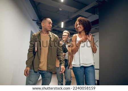 Cheerful company employee flirting with her coworker in the hallway Royalty-Free Stock Photo #2240058159