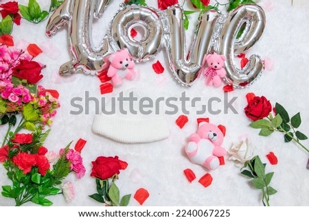 White blank beanie above a fluffy white carpet surrounded by valentine themed decorations
