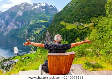 The famous Queen Sonny chair. Elderly tourist rests in this chair. The largest Norwegian fjord Geiranger. Summer trip to Norway.