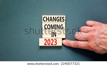 Changes coming in 2023 symbol. Concept word Changes coming in 2023 on wooden blocks. Businessman hand. Beautiful grey table grey background. Business and changes coming in 2023 concept. Copy space.